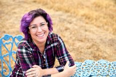 Krystal smiling at a bistro table in a plaid top
