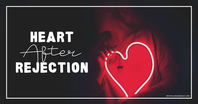 The title text "Heart After Rejection" in a large white font overlaying a woman in a dark room holding a large neon red heart.