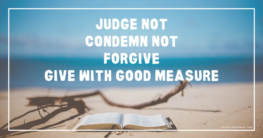The words "Judge not, condemn not, forgive, give with good measure" overlaying a beach landscape with the focus on a Bible laying on the sand with driftwood around it.