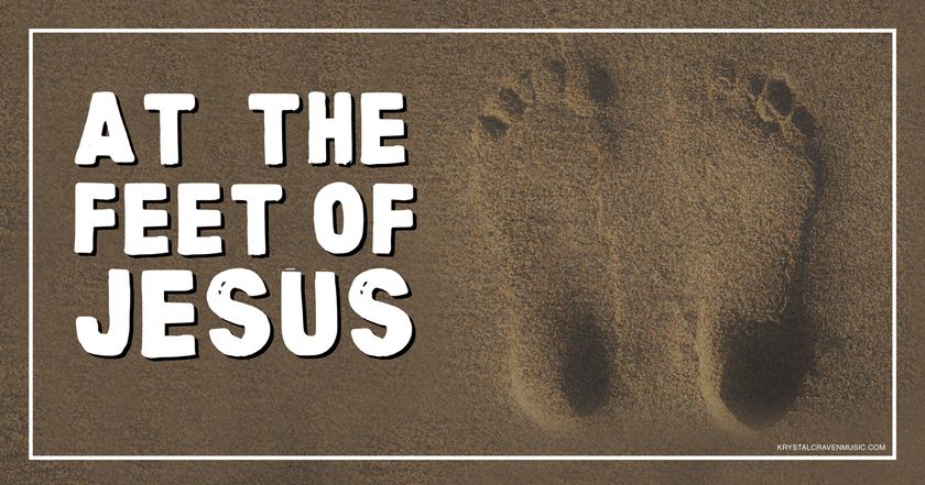 The devotional title text of "At the Feet of Jesus" overlaying feet prints in sand.