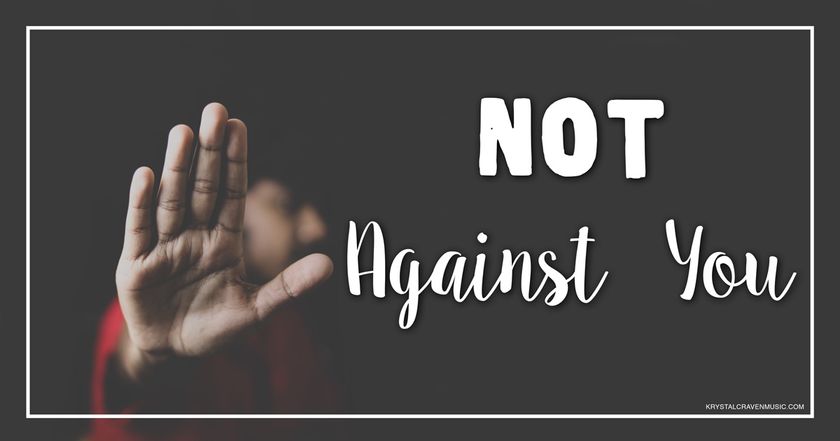 The title text "Not Against You" in a bold white font on a dark background. To the left is an out of focus man holding his hand up in a stop gesture, the hand is in focus.