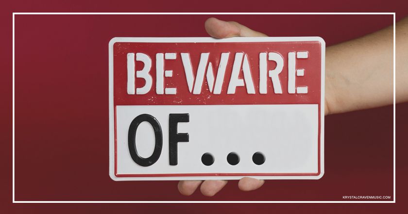 A hand holding a white and red caution sign with the words "Beware Of…" printed on it.